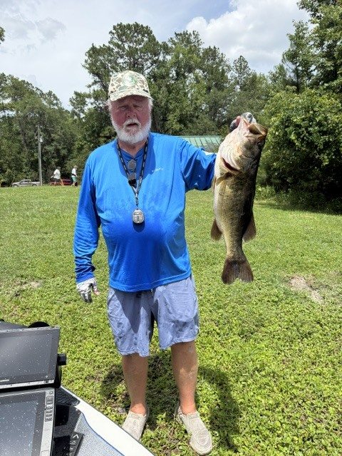 Angler holding a big largemouth bass on the bank