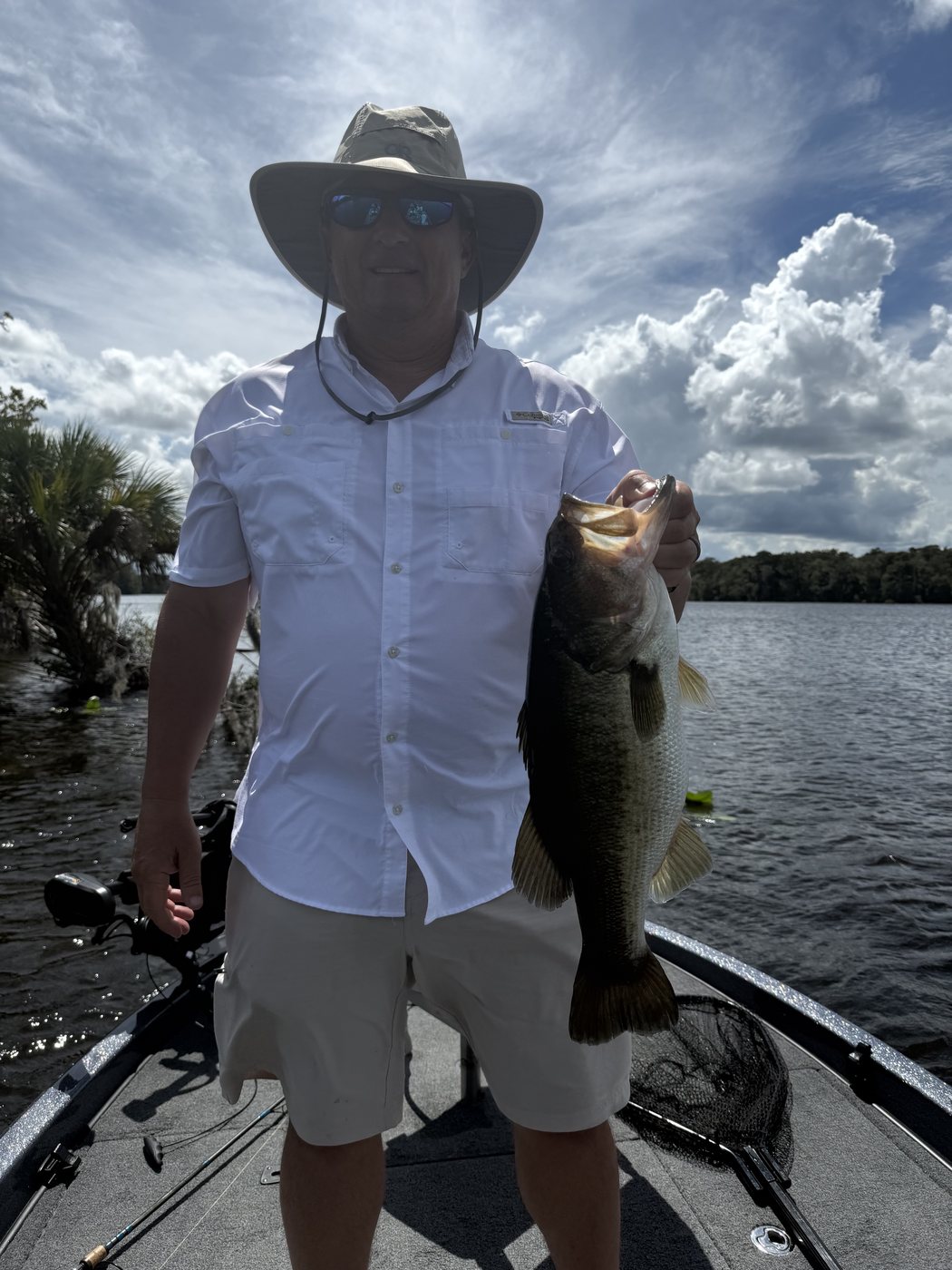 Angler in a wide-brim hat with a largemouth bass caught on a Bass Capital Expeditions guided trip