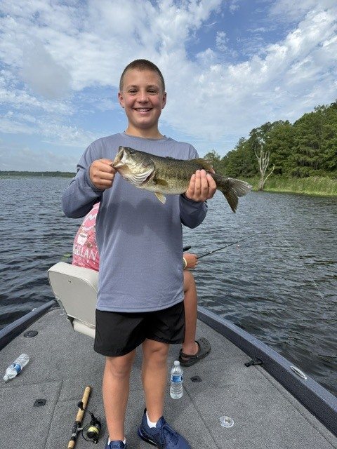 Young angler holding a largemouth bass on a family fishing trip